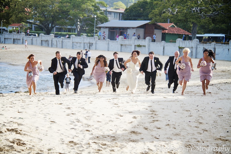 Bridal party start running race on beach - wedding photography sydney